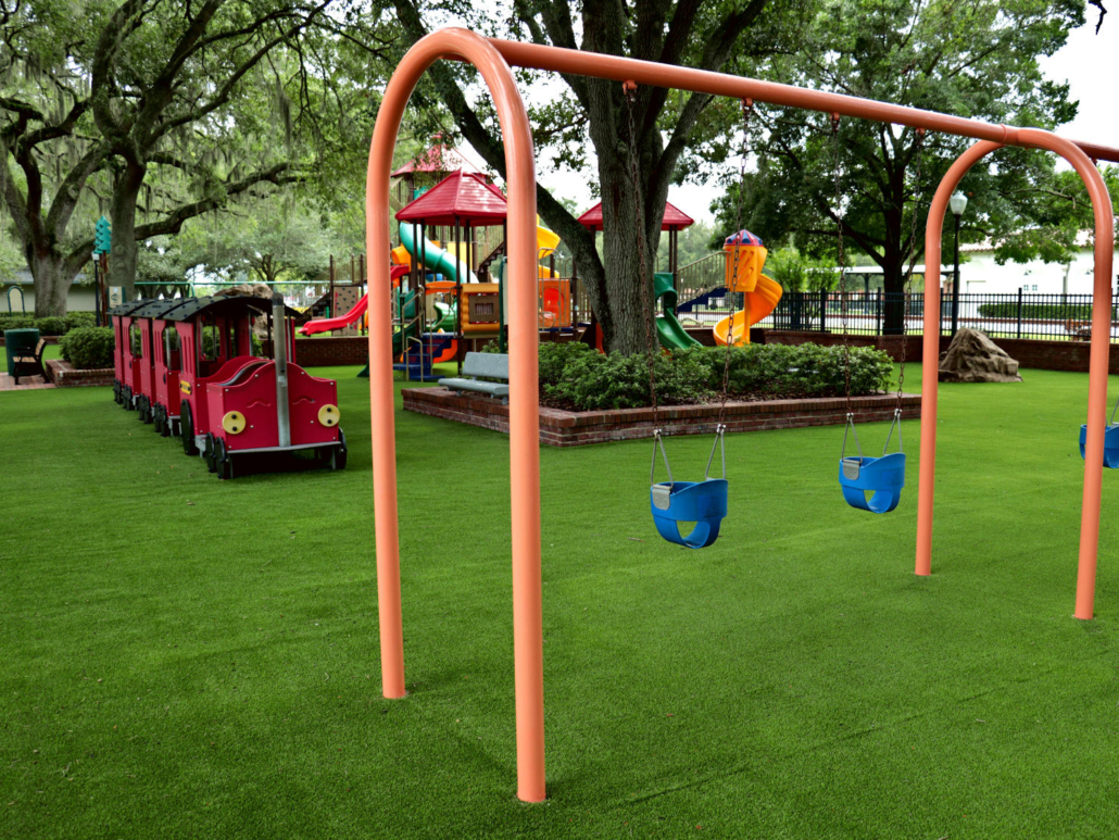 Downtown City Park swing set with playground equipment in background